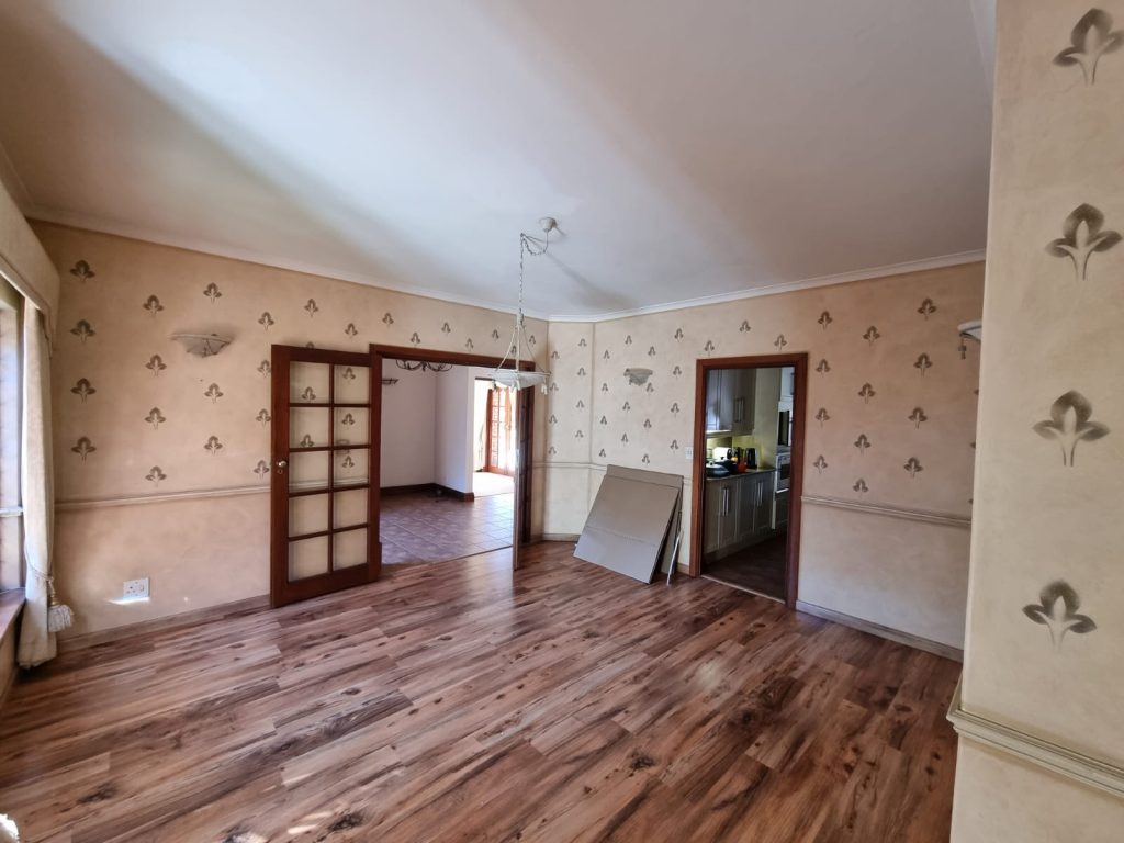 Original living room with patterned wallpaper, dark timber French doors, and refinished wood flooring.