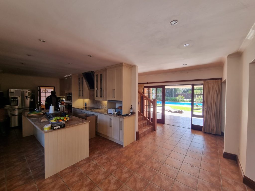 Original kitchen with pale cabinetry and a central island opening onto the pool through glazed doors.