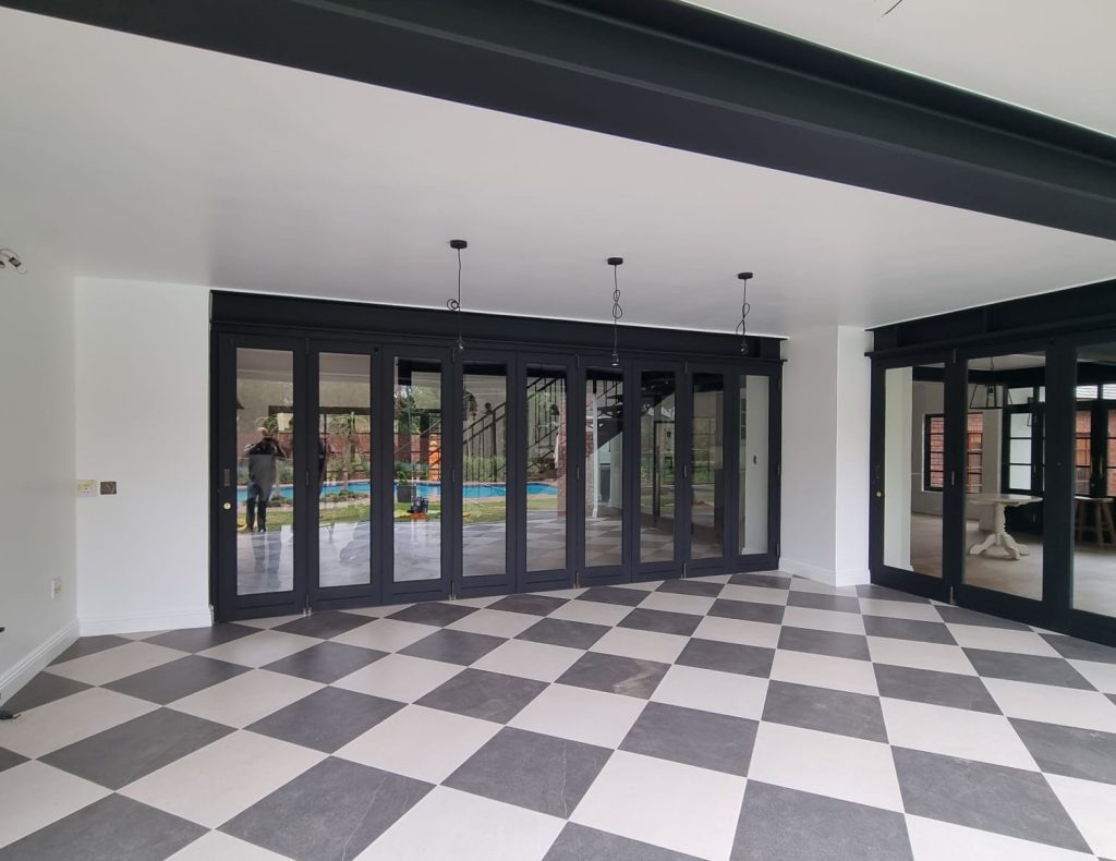 New patio after conversion with black-framed glazing and a chequerboard tiled floor.