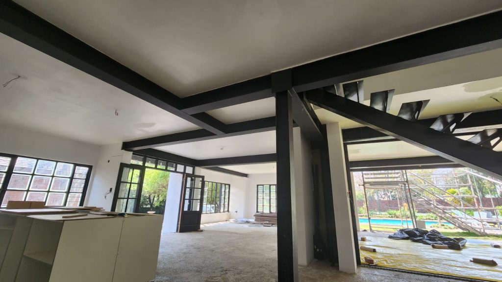 Interior mid-build showing the exposed black steel I-beam grid supporting the floor above.